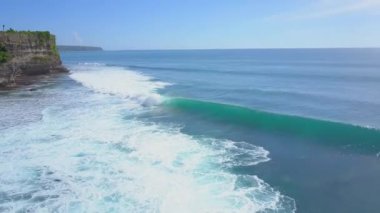 AERIAL: Unrecognizable surfers waiting in line up trying to catch a big wave