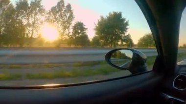 Yaklaş, LENS FlaRE: Ilık altın ışıklı kırsal manzarası boş bir otoyol boyunca seyir eden hareket eden bir spor araba penceresinden. Bir akşam saatlerinde kırsal alan manzarası