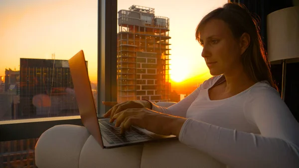 Kanepede Oturan Altın Güneş Işınları Otel Odasını Aydınlatırken Dizüstü Bilgisayarı — Stok fotoğraf