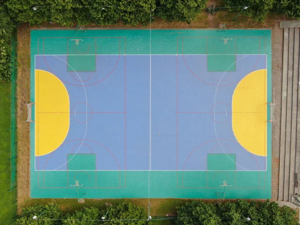 AERIAL, TOP DOWN: Flying away an empty colorful multi sport court near a high school. Cool aerial view of handball goals and basketball backboards around multi colored playground in empty sports park.