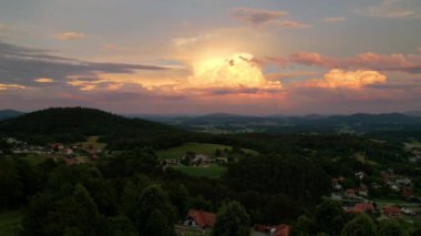 Flying above residential skyscrapers, blocks, flats, houses and homes in beautiful urban city surrounded with forested mountains on gorgeous golden sunrise. Ljubljana cityscape on sunny morning