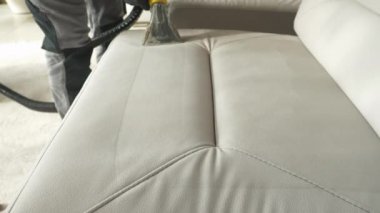 Deep cleaning white upholstered furniture surface with vacuum cleaner. Revealing clean fabric at thorough washing and vacuuming of sofa as a mandatory household chore during spring-cleaning