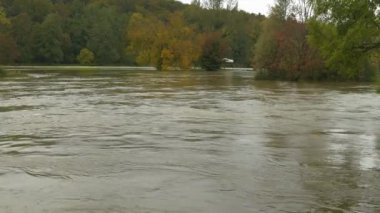 Şiddetli bahar yağmurundan sonra hızlı akan çamurlu bir nehrin su seviyesi yükseldi. Nehir, normal nehir yatağının sınırları içinde zar zor kalan kirli ve güçlü taşkın suyuyla dolu.