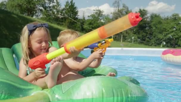 微笑的小孩 瞄准池中的水枪 并在池中飞溅 在一个炎热 阳光灿烂的夏日 与可爱的孩子们在花园游泳池里享受有趣的水活动的欢乐时刻 — 图库视频影像