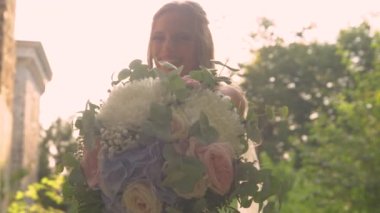 LENS FlaRE, yakın: altın güneş ışığı altında gelin tarafından tutulan görkemli düğün buketi. Gün batımında düğün gününde, yaz çiçeklerinin pastel tonlarında muhteşem bir buket gösteriyor..