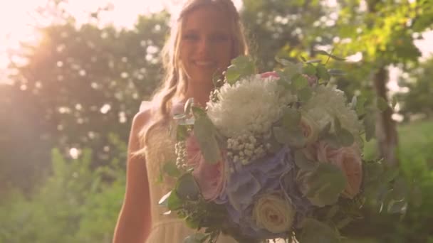 レンズフレア 黄金の太陽の下で花嫁の手に壮大な花束 彼女は誇らしげに豪華な夏の日没の光の中で彼女の結婚式の日にパステルカラーの花の美しい花束を表示します — ストック動画
