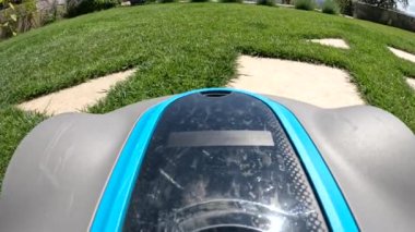POV, görüş açısı: bahçe yolunun etrafındaki yeşil çimleri budayıp duran uzak bir robot biçme makinesi. Bahçede bakımlı çim yetiştirmek için uygun bir bahçe aleti. Güzel bahçeler için modern teknoloji.