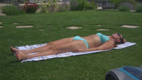 Close Robotic Lawn Mower Disturbs Pretty Woman Having Sunbath Garden — Stock Video