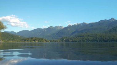 Güneşli bir yaz gününde Bohinj Gölü 'nün dalgalı su yüzeyinde dağ yansıması. Yüksek dağların ve yemyeşil ormanın kucakladığı resimli alp gölü. Maceralar için güzel doğal cazibe.