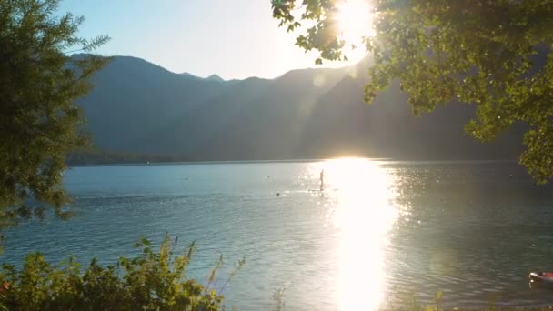 レンズフレア 山に囲まれた美しい高山湖で夏の夕日 スイマーやスタンドアップパドル新鮮な淡水でお楽しみいただけます アウトドア活動のための素晴らしい自然の魅力 — ストック動画