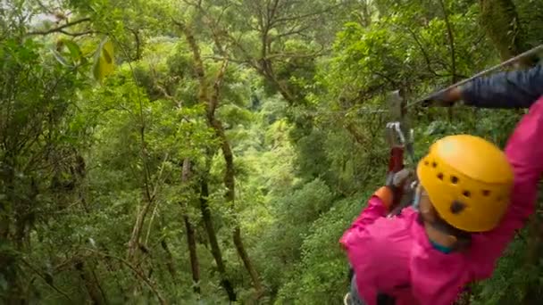 冒険的な女性はジャングルの緑豊かな木のキャノピーを通してジップラインを滑り降りる 彼女は パナマの熱帯雨林の近くの小さな山間の町Boqueteでアドレナリン体験をしています — ストック動画