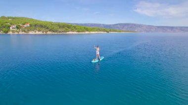 HVAR ISLAND, CROATIA, 05.05.2023: Lady köpeğinin ayağı kaydığında ve derin deniz suyuna düştüğünde ayağa kalkar. Sadık, tüylü arkadaşıyla birlikte Hırvatistan 'ın pitoresk adasında yaz tatillerinde..