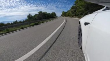 Adriyatik adası Hvar 'ın güzel sahil şeridi boyunca sürüyorum. Güneşli bir günde, güzel manzaralarla çevrili, dolambaçlı yoldaki düz beyaz çizginin yanından geçen ön tekerlek görüntüsü