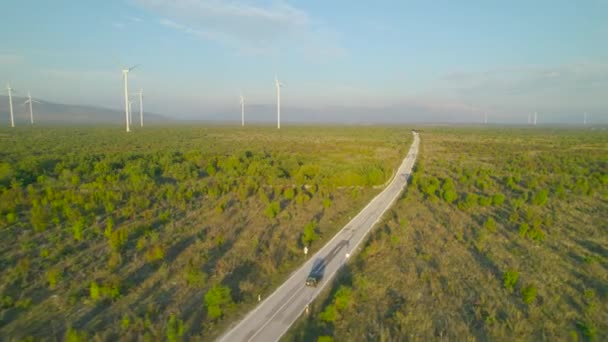 Aerial Suv Poruszający Się Asfaltowej Drodze Przejeżdżający Przez Pracujące Turbiny — Wideo stockowe