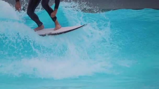 人工波プールパーク 2023 スローモーション 男性サーファーがサーフィンプールで青い波をサーフィンする際に大きなスプレーを作ります 彼はサーフィンのシミュレータで完全に壊れ機械動力の波をサーフィンしています — ストック動画