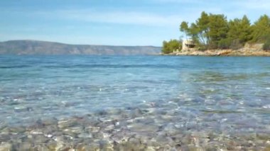 Güneşli Dalmaçya 'daki güzel deniz kıyısında hafif dalgaların rahatlatıcı görüntüsü. Dalgalı Adriyatik Denizi 'nin inanılmaz temiz suları güzel doğal çevrede. Yaz tatili için çarpıcı bir yer..