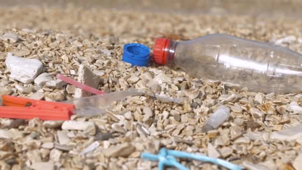 閉じる プラスチックごみを洗浄の驚くべき多様性は 小石の海岸に残っています ゴミで汚染された美しいビーチの悲しい光景 人間の不注意なさは 比類のない自然のイメージを戦利品 — ストック動画