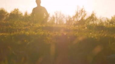 Yaklaş, LENS FlaRE: altın ışıkta çimenli bir yolda koşan bayan atlet. Güzel sabah ışıklarının ilk ışıkları Alp manzarası boyunca yayılıyor. Spor aktiviteleri için güneşli bir sonbahar günü.