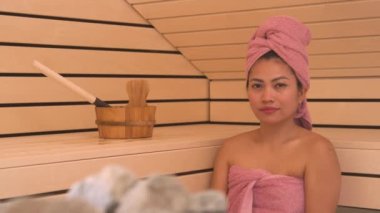 Yaklaş, PORTRAIT: güzel ve gülümseyen Filipinli kadın rahatlatıcı bir saunada. Ahşap Finlandiya saunasında, saunada ve güzellik merkezinde, sakinleştirici ve zehirden arındırıcı tedaviden keyif alıyor..