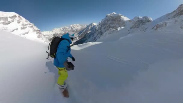 Selfie スノーボードの観光客は 美しいアルバニアアルプスの冒険旅行で雪山を下りながら新鮮な雪を吹き飛ばします 彼は雪山の間の急な手つかずのテラスを乗って楽しんでいます — ストック動画