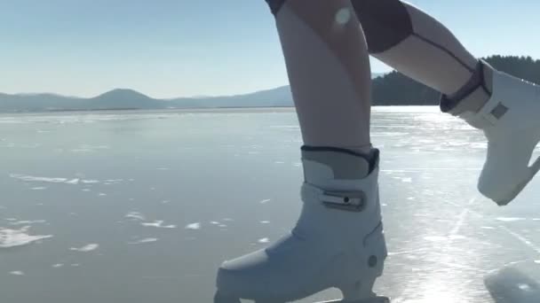 スローモーション レンズフリー 晴れた日には自然に凍った湖でスケートする女性のアイススケートを閉じます 彼女は白いスケートで氷の表面を滑っている 寒い冬のための屋外活動 — ストック動画