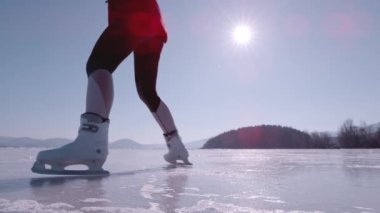 Donmuş gölette tanınmayan kadın artistik patinajı çok yavaş bir harekettir. Doğal bir buz pateni pistinde, harika bir yayılmış kartal figürü sergiliyor. Kış sporları için güzel güneşli bir gün..