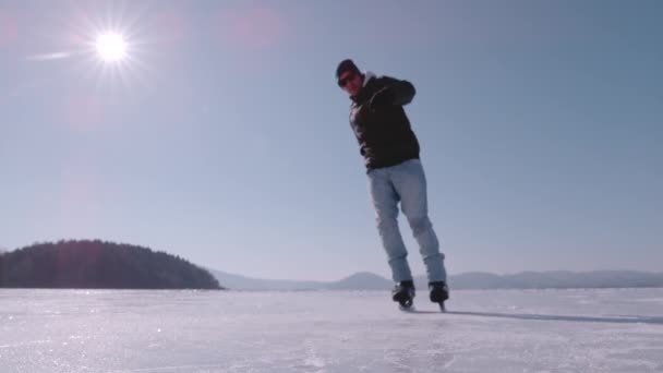 スーパーSlow Motion Close 若い男がスケートでブレーキをかけるときの氷の断片 アクティブな男性は 大きな凍った湖でアイススケートし ホッケーの停車を実践しています 冬のアクティビティのための美しい晴れた日 — ストック動画