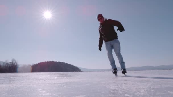 スーパーSlow Motion Close 男性のアイススケーターは ブレーキをかけると氷の断片をスプレーします アクティブな男性は 大きな凍った湖でアイススケートし ホッケーの停車を実践しています 冬のアクティビティのための美しい晴れた日 — ストック動画