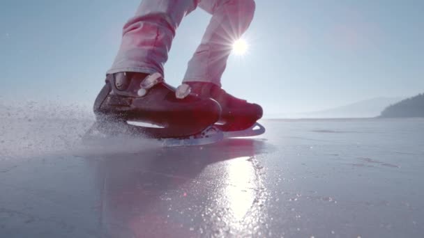 レンズフリー スーパースローモーター クラスアップ 凍った湖でアイススケートしている間 人はブレーキをかけ 停止します 氷の表面に黒いスケートでブレーキをかけ始めると 砕氷した氷の部分が飛び回り始めます — ストック動画