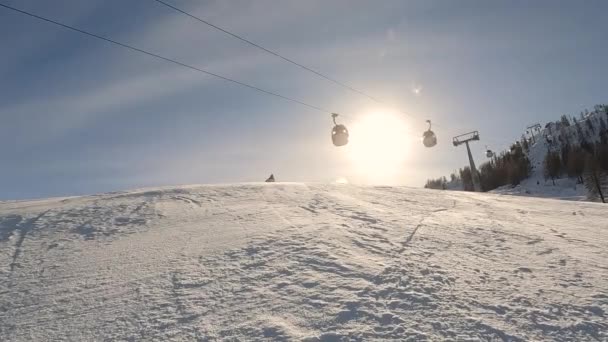 スキーリゾートの斜面に 経験豊富なスキーヤーが彫刻しています 女性は成長したスキーヤードを下りながら旋回するように雪の雲を吹き飛ばします 冬のスポーツのための素晴らしい晴らしい晴れた日 — ストック動画