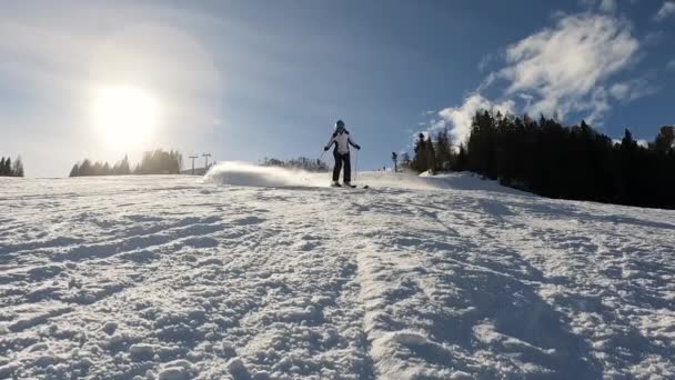 Lens Flare 慢动作 经验丰富的滑雪者在滑雪场上滑行时喷出了厚厚的积雪 年轻的女士正在寒假 在阳光明媚的日子里 她喜欢在雪蒙蒙的奥地利阿尔卑斯山里滑雪 — 图库视频影像