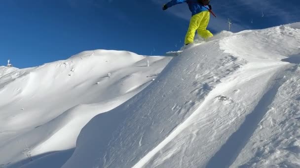 スノーボーダー 極端な男性スノーボーダーがバンプから深い粉の雪にジャンプします 彼は晴れた冬の日にスロベニアアルプスの中心部に新しく雪が降らない山のテラスでスノーボードに乗っています — ストック動画
