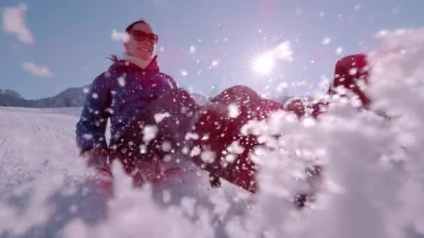 スローモーション Closeの笑顔の女性は 雪のソーサーの上の丘をスライドします 冬の日差しが輝き 雪が吹き飛びながらブレーキをかけている 屋外の冬の活動のための晴れた日 — ストック動画