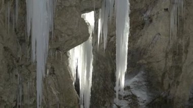 Mostnica Vadisi 'ndeki donmuş bir şelalenin buz saçaklarından su damlıyor. Serbest akan alp nehri ilginç geçitler yaratır ve kayaları yeniden şekillendirir. Ilık güneş ışığı asılı buz çivilerini sıvılaştırır.