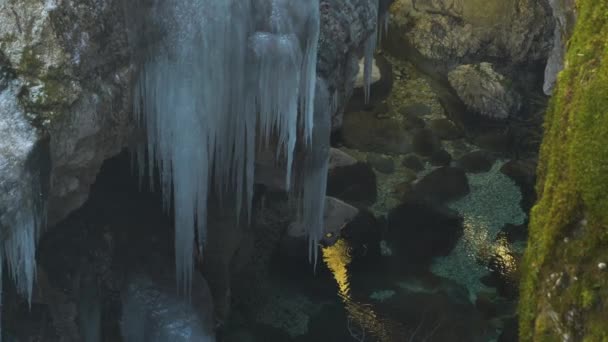 在狭窄的峡谷中 浓密的冰柱悬挂在晶莹清澈的高山溪流之上 滴水结冰形成美丽的冰层 寒冷的冬季里大自然的创造 — 图库视频影像