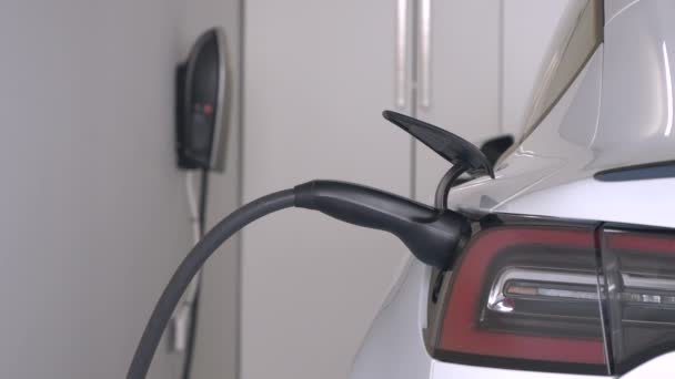连接充电站与电力电缆的电动车 白色电动汽车在家用车库为可充电式发动机电池提供动力 现代运输的有效替代办法 — 图库视频影像