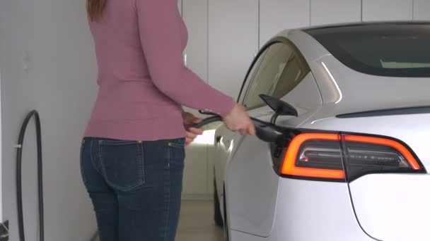 Close Жінка Від Єднує Автомобіль Tesla Від Домашньої Зарядки Від — стокове відео