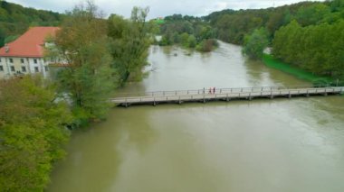 Bir grup turist, Krka Nehri 'nin üzerinde, köprüyü yürüyerek geçiyorlar. Meçhul insanlar yüksek su seviyesiyle çamurlu bir nehri geçiyorlar. Sonbahar yağışından sonra nehir taşmış durumda..