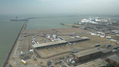 DOVER PORT, BİRLİK KINGDOM, EYLÜL 2023: BİRLİK ANGLE Görünümü: Bir liman terminalinin giriş noktasındaki kamyonlar ve yolcu araçları ve Manş Denizi 'ni geçtikten sonra limana gelen büyük bir feribot.