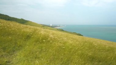 Yeşil çimenler sallanıyor ve kayalıklardan esen yumuşak yaz rüzgarında hışırdıyor. Bulutlu bir yaz gününde derin mavi okyanusun üzerinde çayırları dalgalandırmak. Güney İngiltere 'nin resimli kıyı şeridini araştırıyoruz..