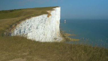 Geleneksel deniz feneri Güney İngiltere 'de güzel beyaz uçurumların sonunda. Güneşli bir gün ve mavi okyanus boyunca uzanan dağılan tebeşir duvarlarının üzerindeki çimenli uçurumlarla muhteşem bir kıyı şeridi..