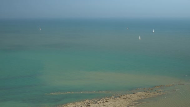 多风的夏日 帆船在五彩缤纷的波浪形大海中环绕着海角航行 探索着英格兰南部风景如画的海岸 海流形成一个有趣的褐色和绿松石色调色板 — 图库视频影像