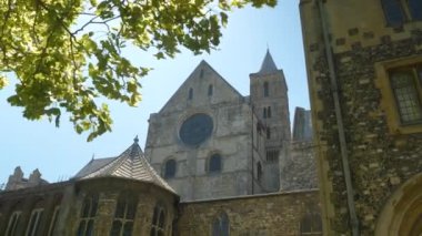 Güneşli bir yaz gününde, yeşil ağaç tepesinin altından tarihi bir katedralin dış cephesi. Görkemli Canterbury Katedrali Romanesk ve Gotik mimari tarzların bir karışımı..
