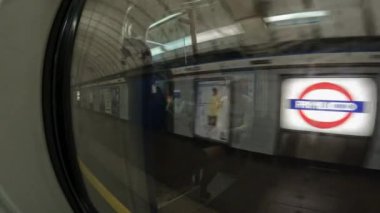 LONDON, BİRLİK KINGDOM, 15 EYLÜL 2023: Boş bir istasyondan ayrılan metro treninin penceresinden yansıtıcı görüş. Metro, reklam posterleriyle istasyondan ayrılır ve karanlık bir tünele girer..