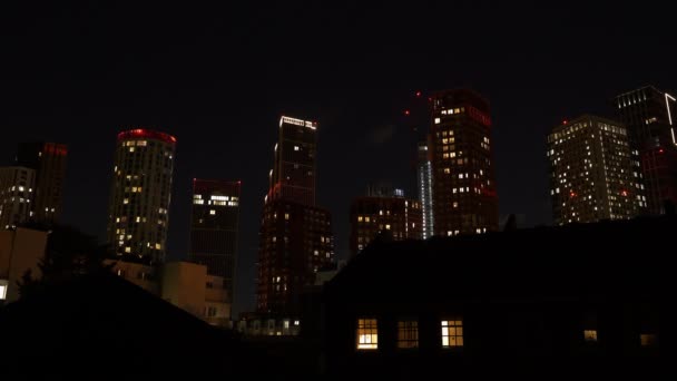 タイムラプス 暗い夜空の下に高い都市の高層ビルの輝く窓ライト 夜のロンドン地区の近代的な商業および住宅の建物が付いている壮大な都市風景 — ストック動画