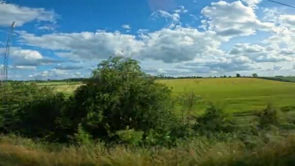 Pov 緑の田園地帯を通るリラックスした乗り物の間の列車窓からの眺め 過去の農地や牧草地を列車で移動するための美しい晴れた日 それらの間に村が表示されます — ストック動画