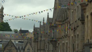 Güzel eski ortaçağ kasaba evleri arasında dalgalanan renkli bayraklar. Bunting bayraklarıyla süslenmiş tarihi binaların resimli taş cepheleri. Tarihi şehrin eski bölümünde şenlik havası.