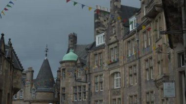 Renkli bayrakları olan eski kasaba evlerinin büyüleyici taş cepheleri. Ortaçağ şehir merkezinde rüzgarda dalgalanan parlak renkli bayraklar. Tarihi kasabada şenlik havası.