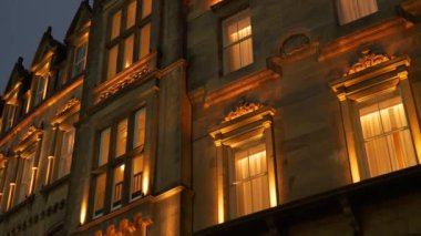 Akşam alacakaranlığında eski bir evin güzel bir mimarisi var burada. Günbatımında beyaz çerçeveli aydınlık pencereler etrafında şaşırtıcı detaylarla ortaçağ taş cephesi.