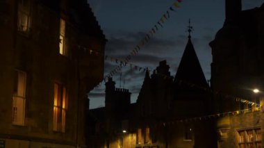 Şehrin tarihi bir bölgesindeki inanılmaz ortaçağ binaları siluetleri. Hoş kasaba evleri arasında asılı renkli bayraklar akşam rüzgarında sallanıyor. Geceleri güzel aydınlatılmış taş cepheler..